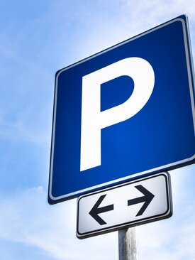 Blaues Verkehrsschild mit weißem „P“ für Parkplatz, darunter Richtungspfeil in beide Richtungen