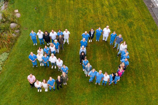 Mitarbeitende der Schön Klinik Bad Aibling Harthausen bilden die Zahl 30 zum Jubiläum auf einer Wiese