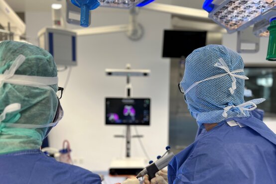 Zwei Chirurgen führen im modernen Operationssaal eine Kniegelenkoperation mit computerassistierter Navigation durch