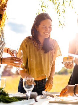 Vier junge Erwachsene stehen im Freien an einem gedeckten Tisch