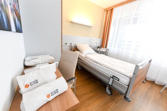 Einzelzimmer in der Schön Klinik Düsseldorf mit großem Fenster, Einzelbett, Sessel und TV