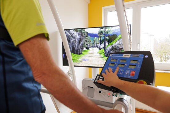 Aktive Bewegungstherapie am Gangtrainer in einem modernen, hellen Therapieraum.