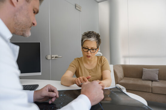 Orthopäde bespricht Röntgenbefunde mit Patientin in moderner Praxis am Schreibtisch