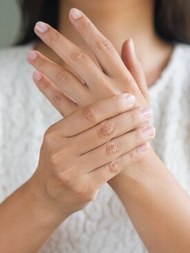 Frau hält ihr rechtes Handgelenk, Nahaufnahme zur Veranschaulichung