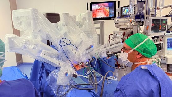 Chirurg bedient Operationssystem für robotergestützte Chirurgie im OP-Saal, Operationsroboter mit steriler Abdeckung